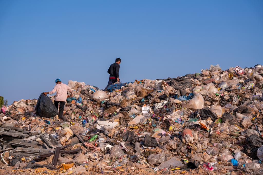 Two waste pickers sort plastic at an open dumpsite, illustrating plastic credits and a fair circular economy