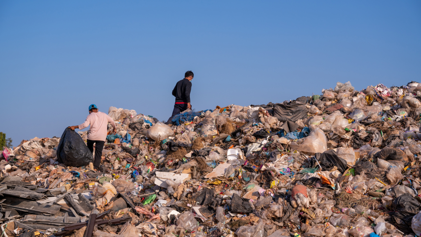 Two waste pickers sort plastic at an open dumpsite, illustrating plastic credits and a fair circular economy